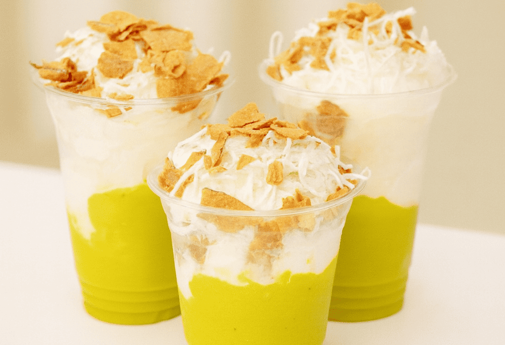 Creamy green avocado ice cream, garnished with fresh avocado slices and a drizzle of coconut milk